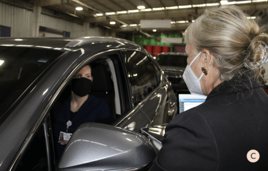 woman sitting in the car with a mask at a drive-through site